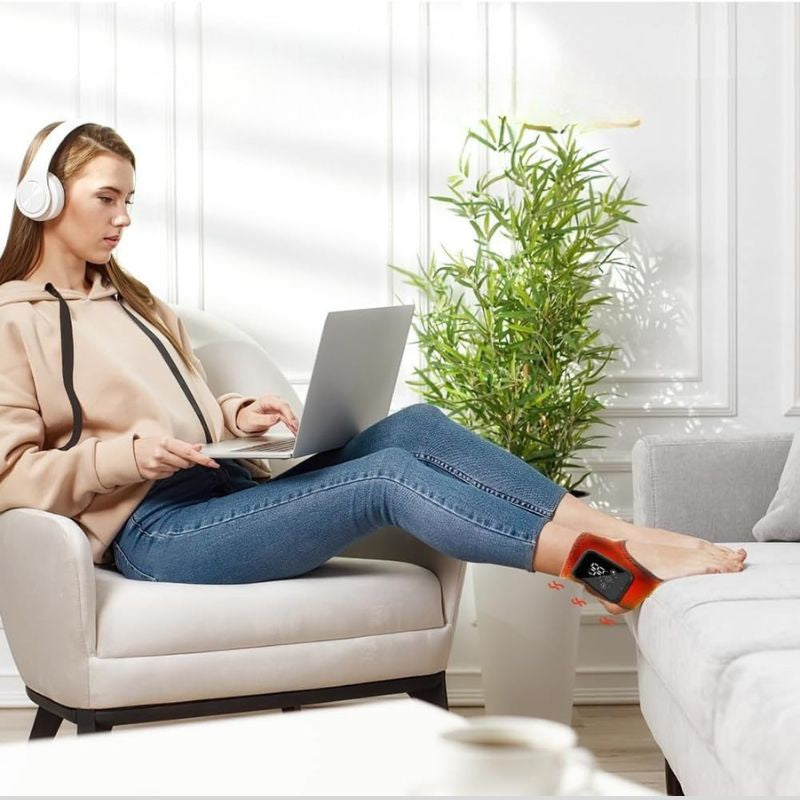 Femme en télétravail utilisant l'attelle chauffante de cheville Soulavi installée confortablement sur le canapé