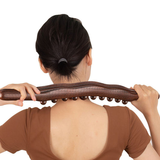Femme de dos massant sa nuque et ses trapèzes avec le bâton de massage en bois à deux mains