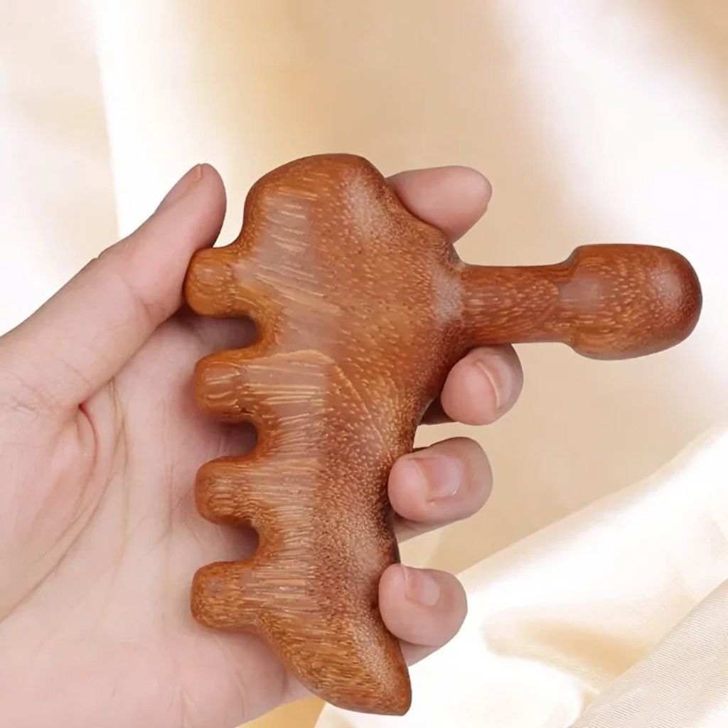 Gros plan sur la forme sculptée en bois de l'outil Gua Sha tenu dans le creux de la main