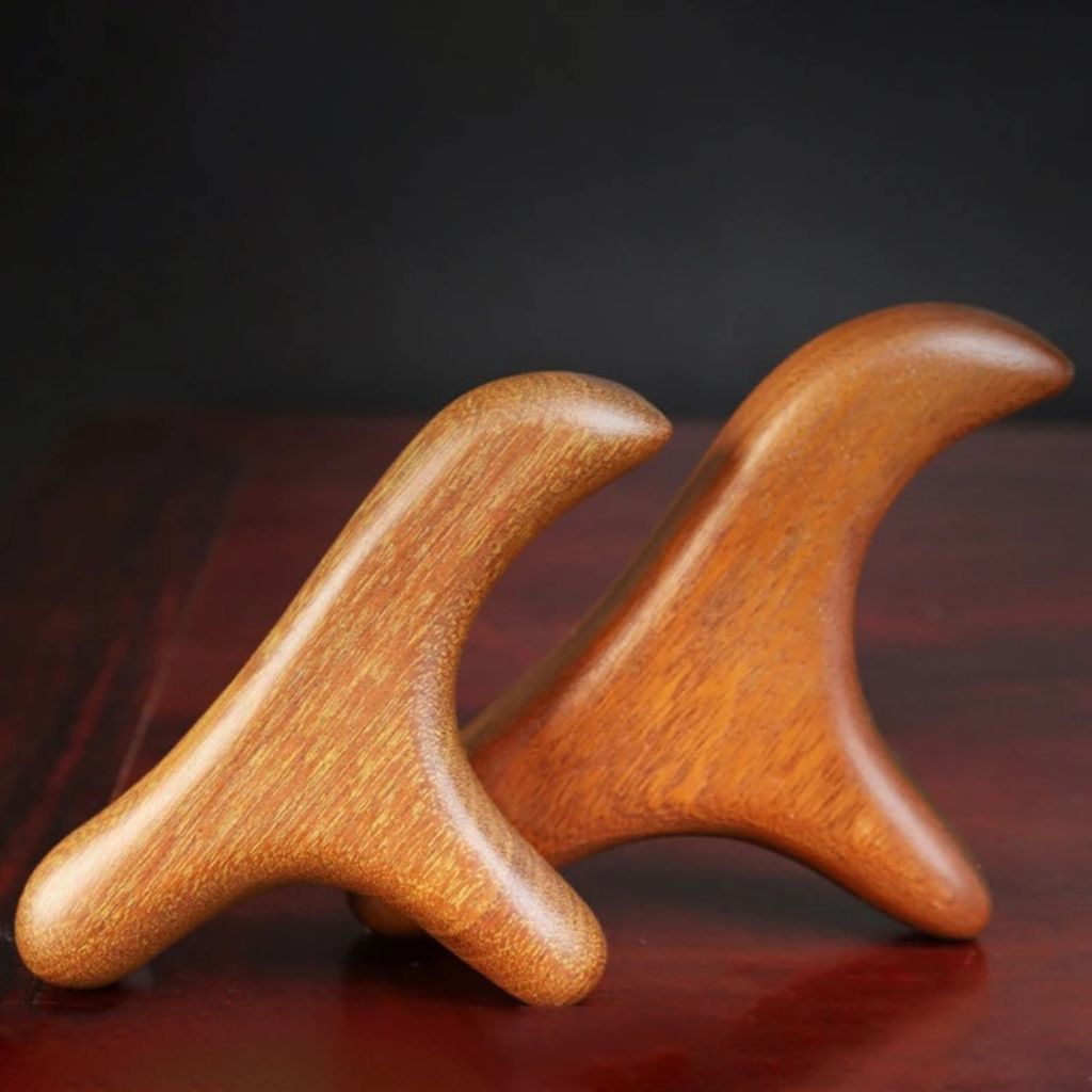 Deux outils Gua Sha en bois de santal massif posés sur une table en bois, vue de profil mettant en valeur le veinage