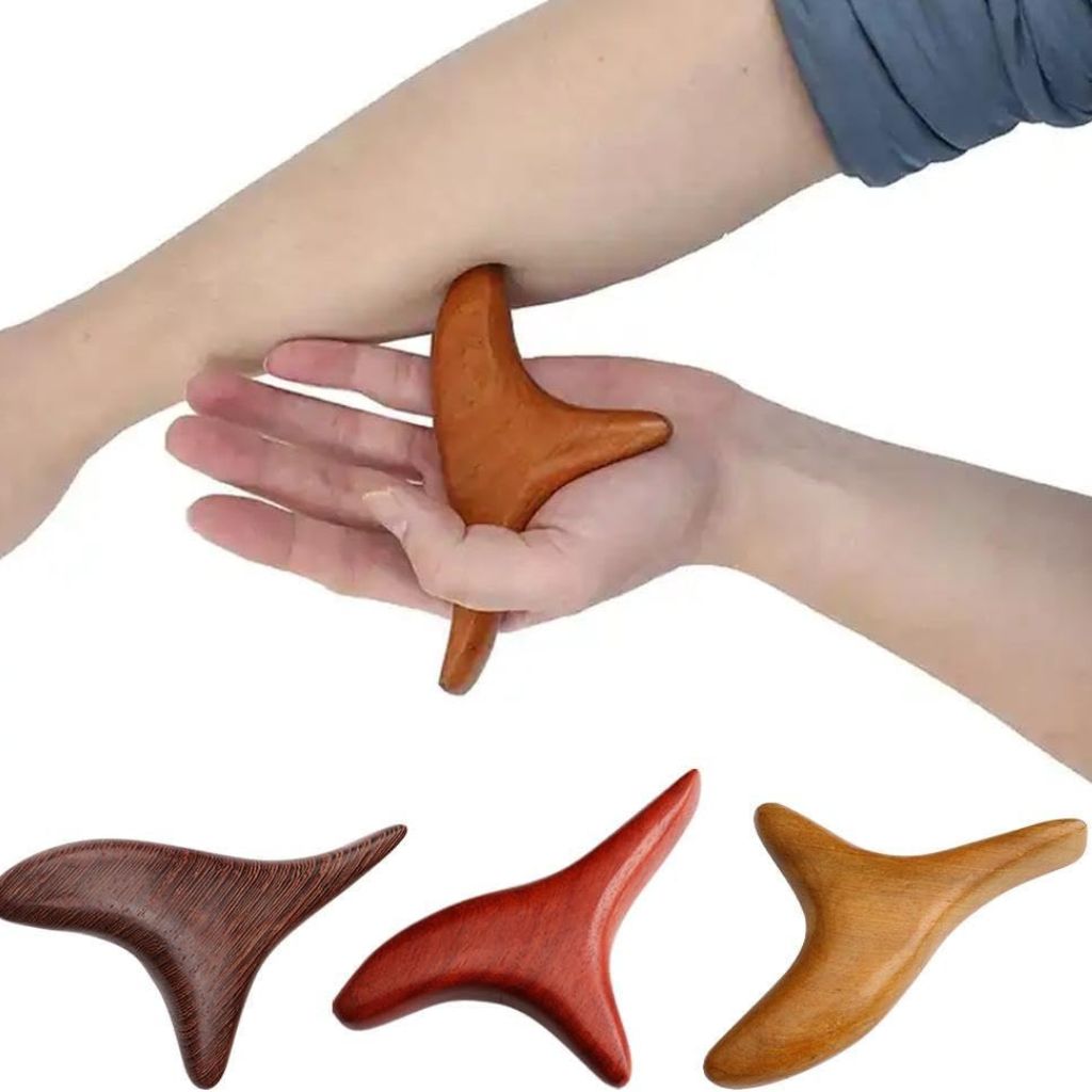 Outil Gua Sha en bois de santal tenu dans la paume contre l'avant-bras, trois variantes de couleurs en bas de l'image