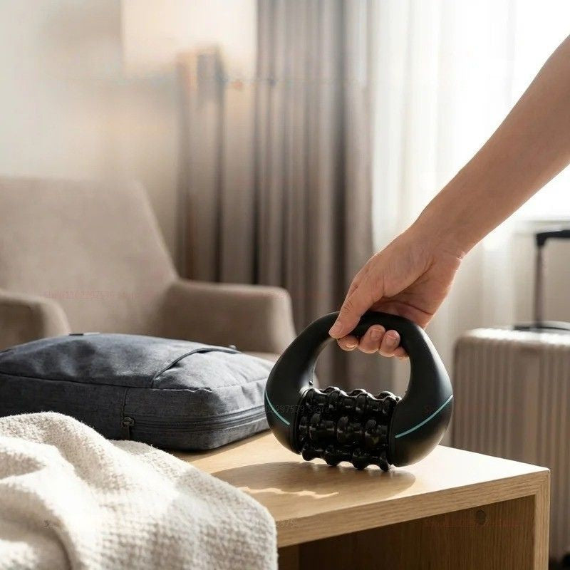 Masseur électrique Soulavi tenu à la main dans une chambre d'hôtel avec valise — portable rechargeable voyage