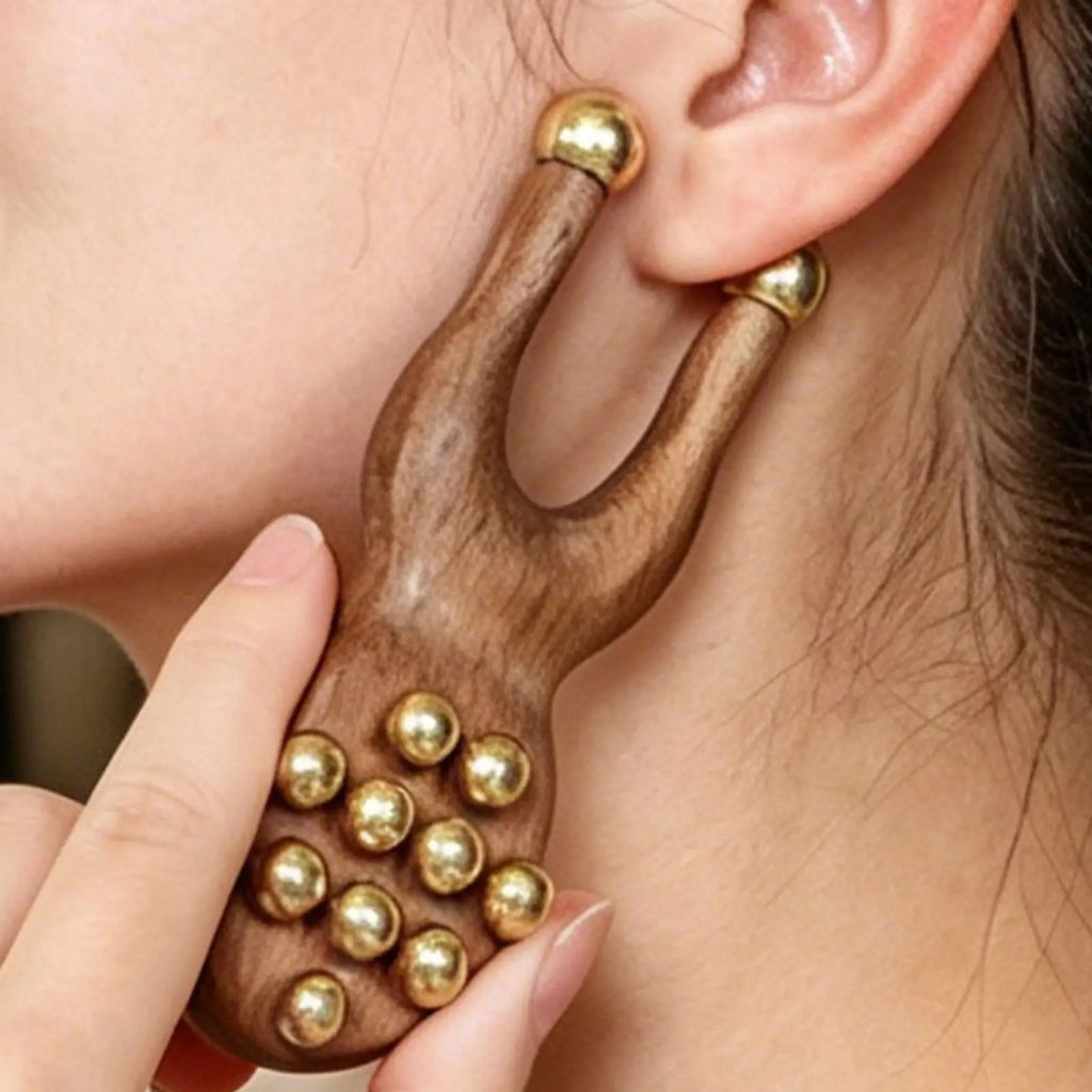 Gros plan de la fourche du masseur facial en bois positionnée le long de la mâchoire et de l'oreille