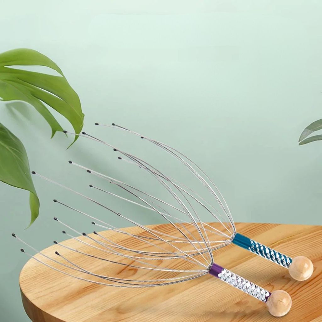 Deux masseurs de tête Octopus posés sur une table en bois avec une plante verte, griffes déployées montrant leur flexibilité
